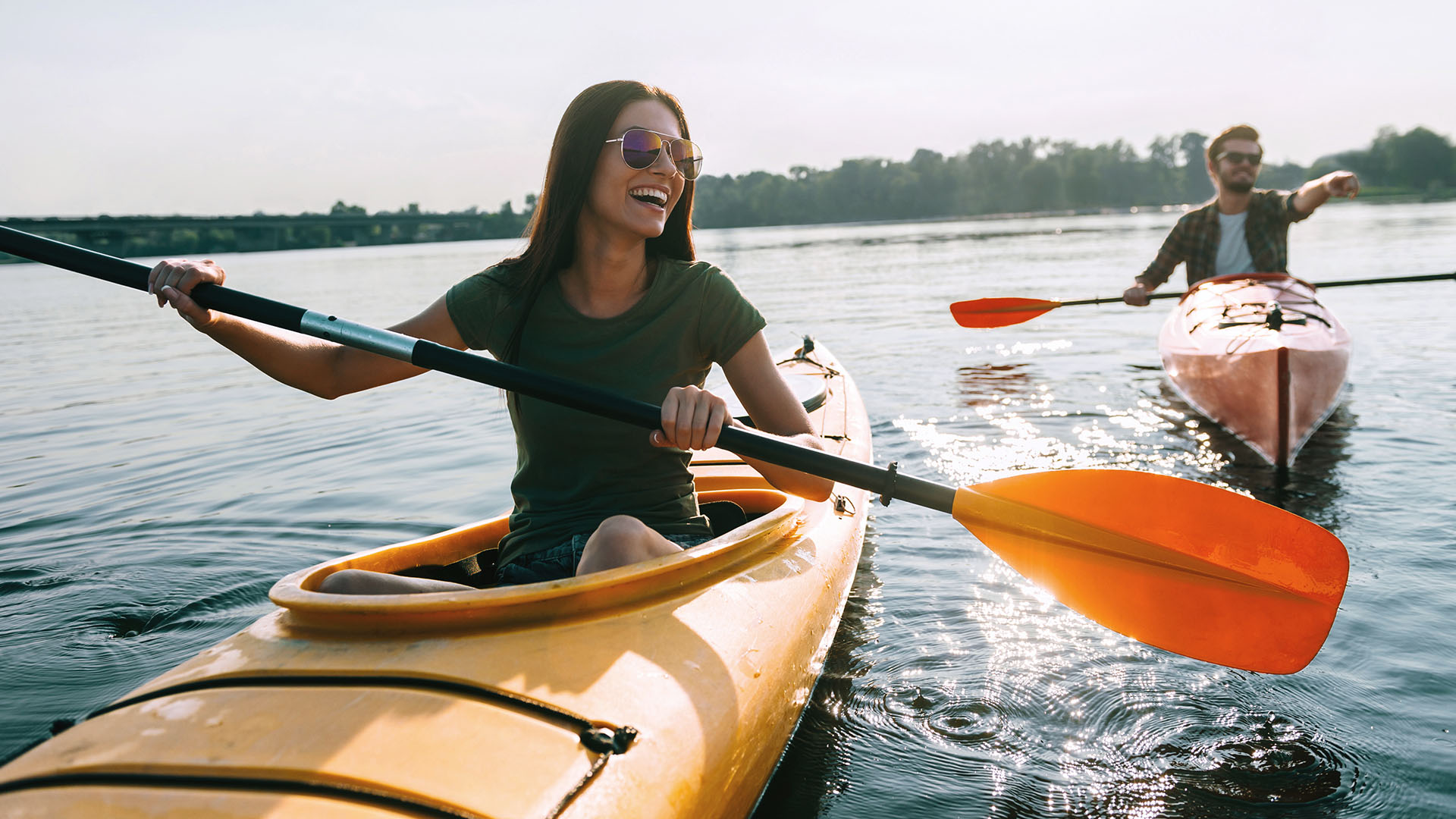 A happy young woman and man are kayaking on a sunny lake