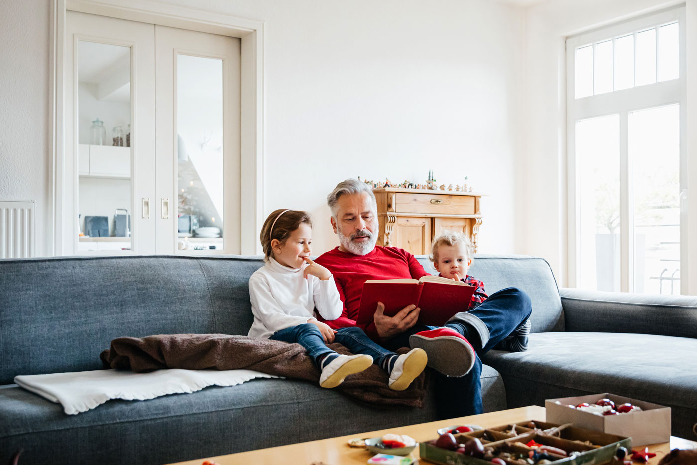 Two young grandchildren sitting with grandpa reading