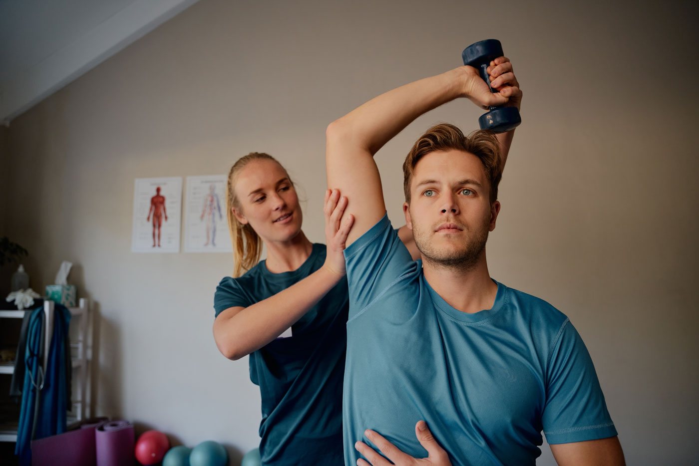 Young female physiotherapist helping patient to strengthen arm